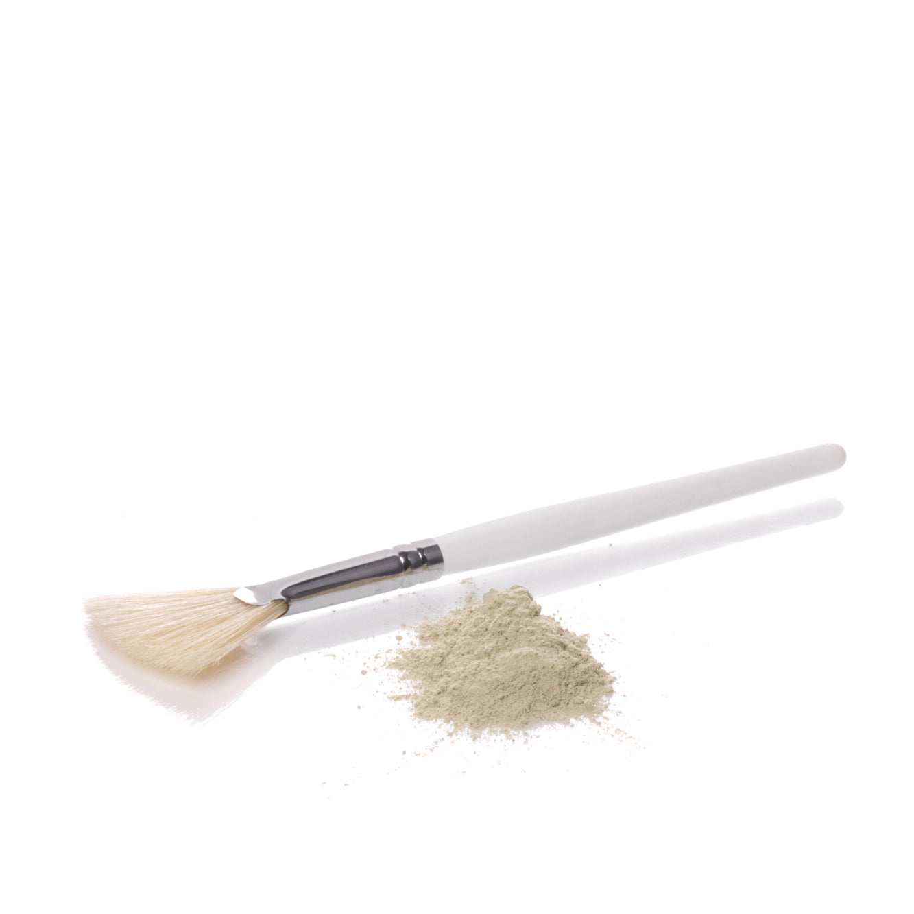 Brush shown on white background with small pile of matcha mask alongside 